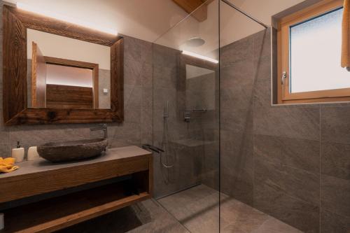 a bathroom with a sink and a glass shower at Chalet Resort Innerluferhof in Rifiano