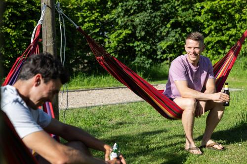 two men sitting in a hammock with bottles of beer at Yart in Scharendijke