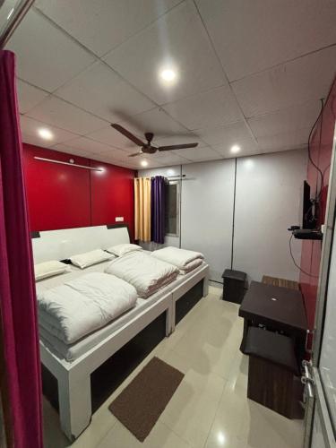 a bedroom with two beds and a red wall at Hotel Om Palace in Ukhimath