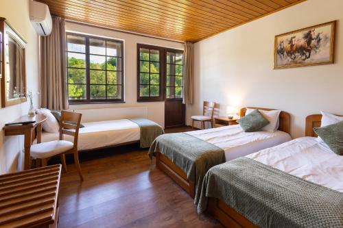 a room with two beds and a chair and windows at Bashtinata stryaha Guest rooms and Natural pool in Beli Osŭm