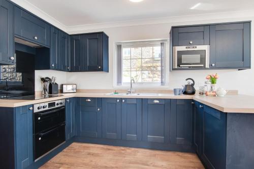 a kitchen with blue cabinets and a sink at Northern Hideaways, Iona Cottage in Newcastle upon Tyne
