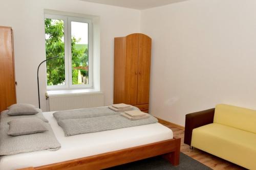a bedroom with a bed and a yellow chair at Apartmány BRETZ in Vrbov