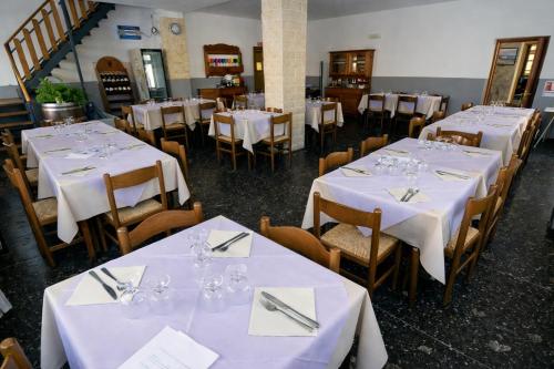 a row of tables in a restaurant with white table settings at Hotel Degli Angeli in Pontinvrea