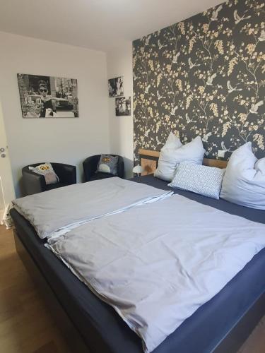 a bedroom with a large bed with two chairs at Ferienwohnung Dreiländereck Gronau in Spechtholzhock