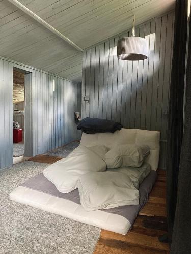a large white bed sitting on the floor in a room at Pelēkā Māja, forestside getaway house for cosy stays in Myza Brenguli