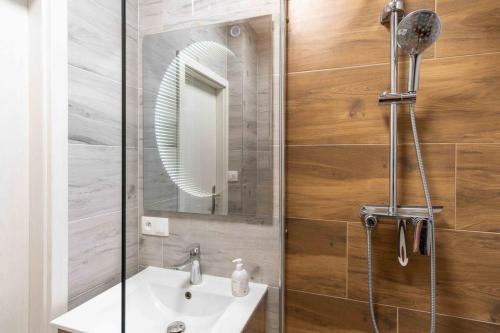 a bathroom with a sink and a shower with a mirror at Tatra's View Apartment in Poprad