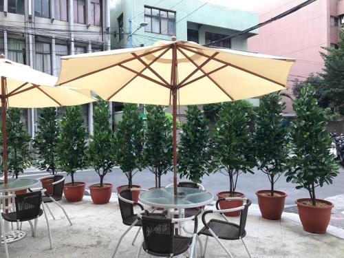 a table and chairs with an umbrella and trees at Single Inn - Taipei in Taipei