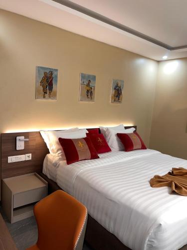 a bedroom with two beds and a orange chair at Teral Hotel by Fleur de Lys in Dakar