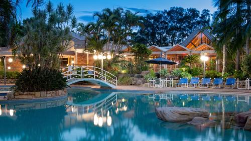 a pool at a resort at night with a bridge at Boambee Bay Resort in Bonville