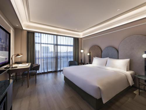 a hotel room with a large bed and a desk at Mercure Beijing Zhongguancun in Beijing