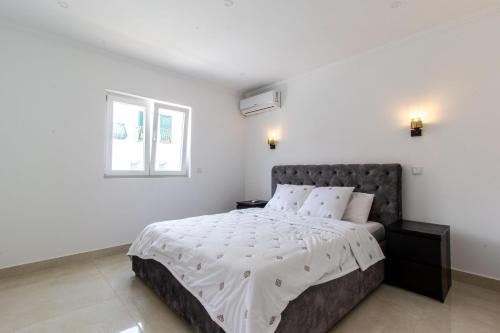 a white bedroom with a large bed with white sheets at Castelo Sereno in Quinta do Conde