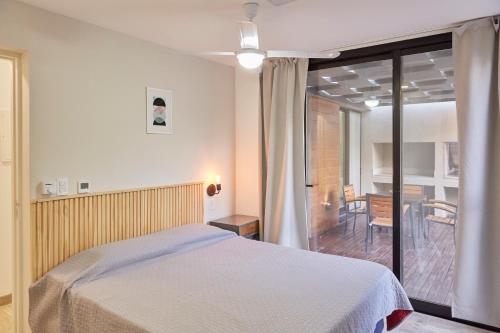 a bedroom with a bed and a balcony with a table at Entre Montañas - Vista Calma in Potrerillos