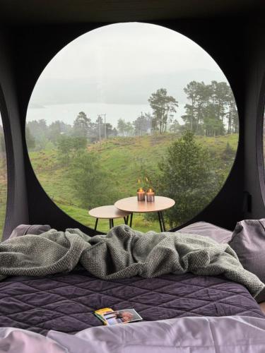 a bed and a table in a round window at Birdbox Forland in Stord