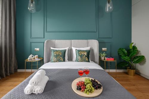 a bed with two glasses of wine and a plate of fruit at Lumina I Premium 3-room Apartments with Parking I Balcony I Manufaktura in Łódź