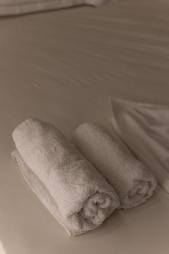 two rolls of white towels sitting on a bed at Sea La Vie Hotel in Durrës
