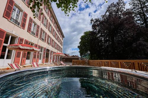 a swimming pool in front of a building at Le Parc - Hôtel & Spa in Allevard
