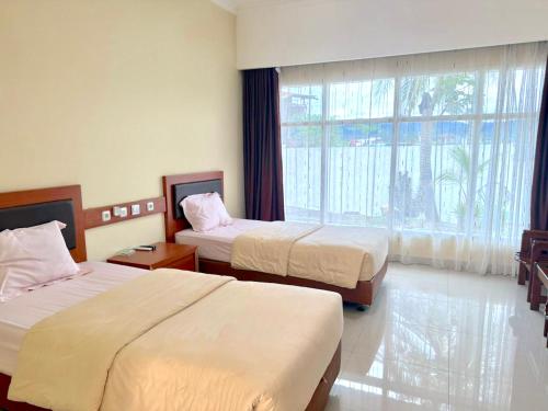 ein Hotelzimmer mit zwei Betten und einem großen Fenster in der Unterkunft Hotel Caredek in Solok