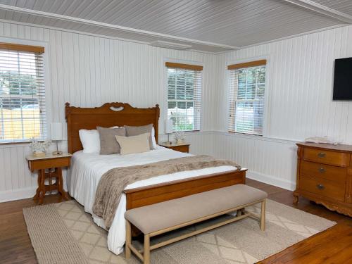 a bedroom with a bed and a tv and windows at 02-Sandbar Suite at The Castle Inn in Ocracoke