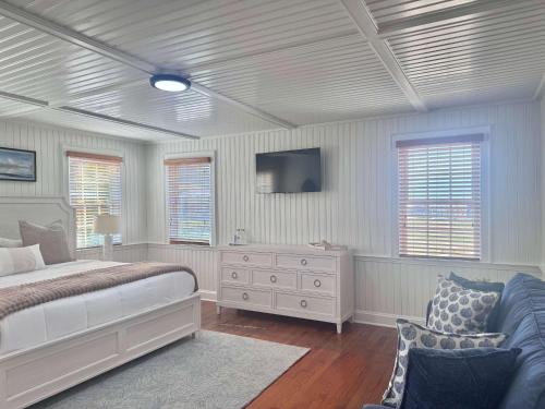 a bedroom with a bed and a couch and windows at 04-The Seashell Suite at The Castle Inn in Ocracoke