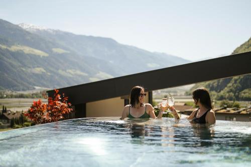 two women sitting in a hot tub with glasses of wine at Amaris Suites Rabland, Südtirol in Rablà
