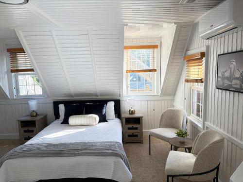 a bedroom with a bed and a chair and windows at 08-Flight Suite at The Castle Inn in Ocracoke