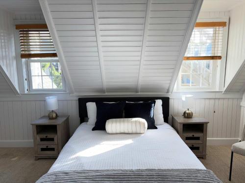 a bedroom with a large bed with two windows at 08-Flight Suite at The Castle Inn in Ocracoke