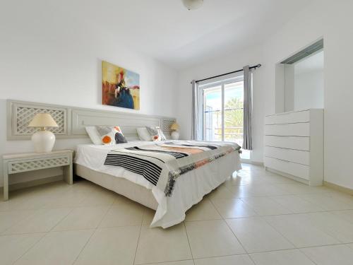 a white bedroom with a bed and a window at Sunset Haven Algarve in Albufeira