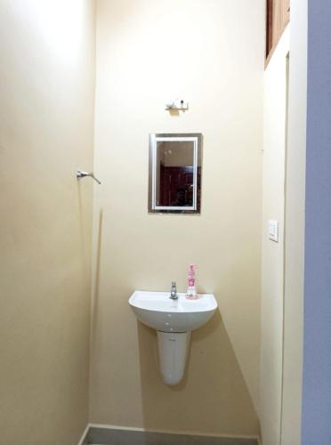 a bathroom with a white sink and a mirror at Happy Stay in Vagamon