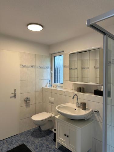 a white bathroom with a toilet and a sink at Birkenweg Ankerplatz II in Carolinensiel