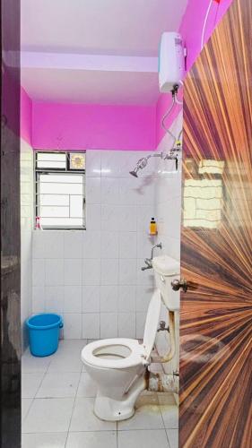 a bathroom with a toilet and a pink ceiling at Kaushani Homes in Nangi