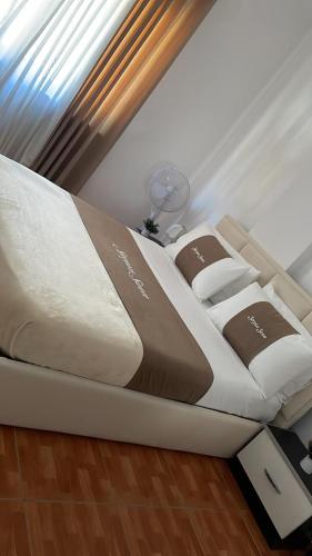 a white bed with brown and white pillows on it at Sea You Soon Apartment in Shëngjin