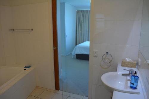 a bathroom with a sink and a shower and a bed at Wallaroo Marina Luxury Apartment in Wallaroo