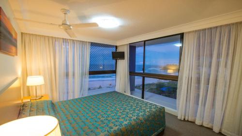 a bedroom with a bed and a large window at Beach House Seaside Resort in Gold Coast