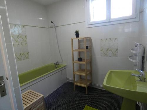 a bathroom with a green tub and a sink at Champan in Toulouzette