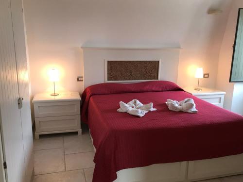 a bedroom with a red bed with two white towels at Relais Masseria della Colomba - Agriturismo in Francavilla Fontana
