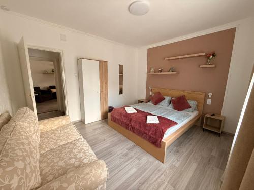 a small bedroom with a bed and a couch at Balaton Bloom Vendégház in Siófok