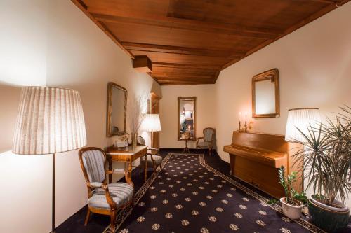 a living room with a piano and a chair at TH Samedan - Hotel Bernina 1865 in Samedan