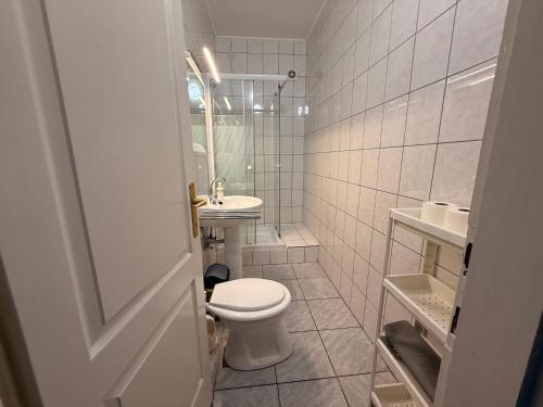 a white bathroom with a toilet and a sink at Balaton Bloom Vendégház in Siófok