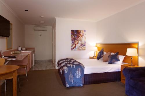 a hotel room with a large bed and a kitchen at White Lace Motor Inn in Mackay