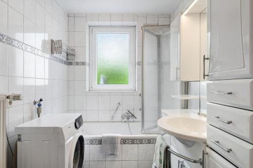 a white bathroom with a washing machine and a sink at Ferienwohnung Am Seebach, 80 Qm in Titisee-Neustadt