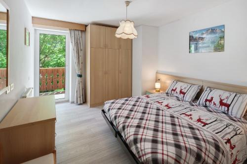 a bedroom with a bed and a desk and a window at Appartamenti Lella in Vigo di Fassa