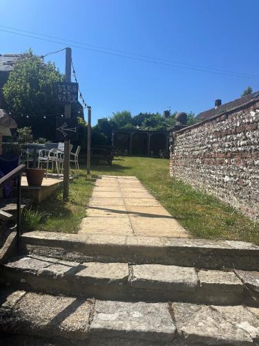 a stone path next to a brick wall with a table at The Village House in Findon