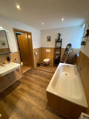 a bathroom with a tub and a sink and a toilet at Racoon Lounge in Bad Liebenstein