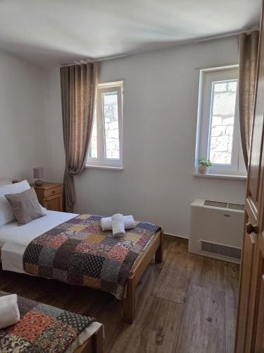 a bedroom with a bed and two windows at Guest house Jere Old Town in Rogoznica