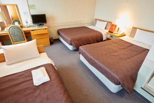 a hotel room with two beds and a desk at Hotel Select Inn Aomori in Aomori