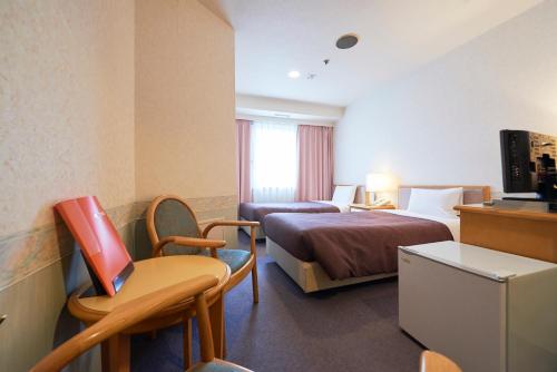 a hotel room with two beds and a desk at Hotel Select Inn Aomori in Aomori
