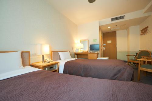 a hotel room with two beds and a table at Hotel Select Inn Aomori in Aomori