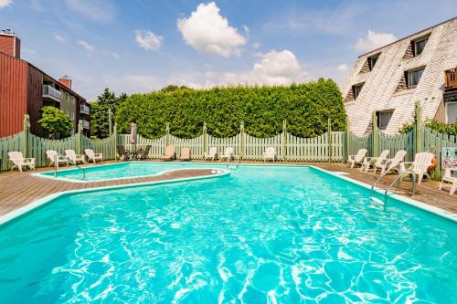 a swimming pool with chairs and a fence at Pool & Spa - Chalet Le Misco in Beaupré