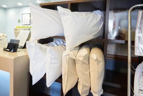 a shelf with white pillows and boots on it at Hotel Select Inn Aomori in Aomori