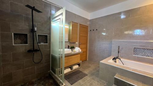 a bathroom with a shower and a sink and a tub at Villa de détente "Tombosoa" avec vue sur la baie de Diego-Suarez in Antsiranana